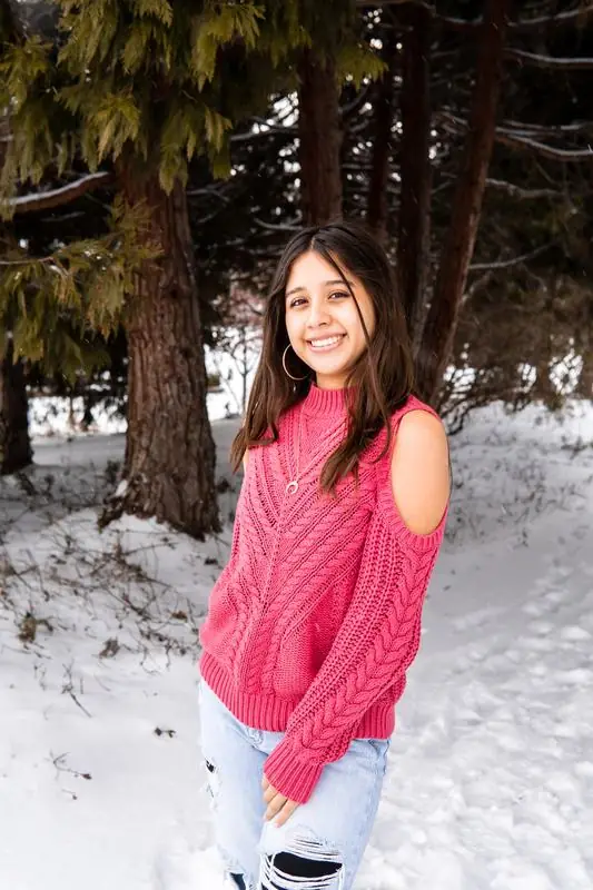 Girl in a pink sweater in a snowy forest