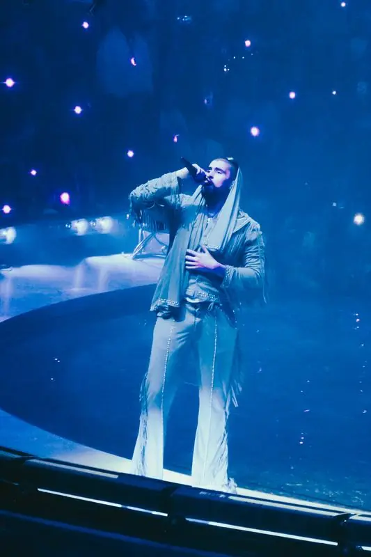 Performer in a hooded outfit under blue light