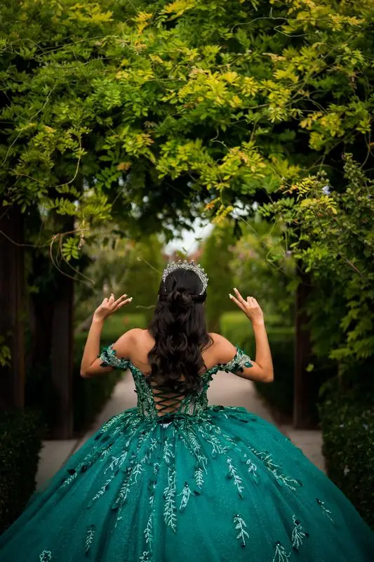 Girl in a green ball gown under a leafy archway