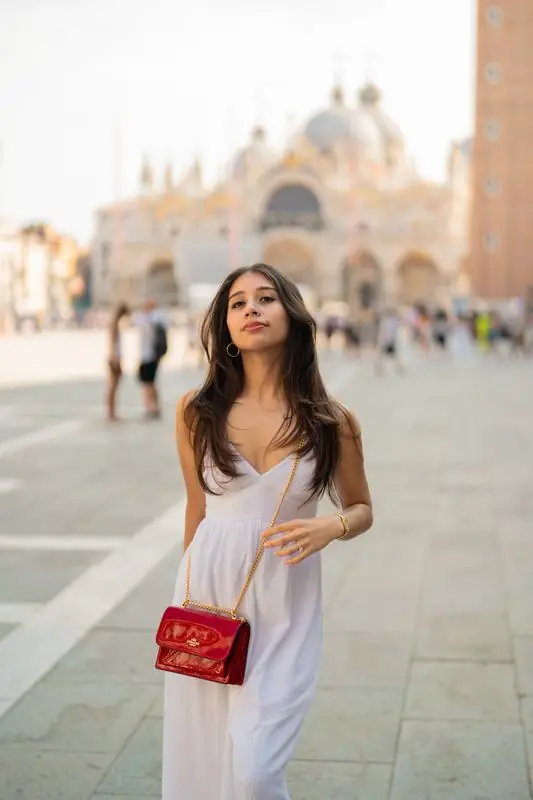 Woman in white dress with a red purse in a city square