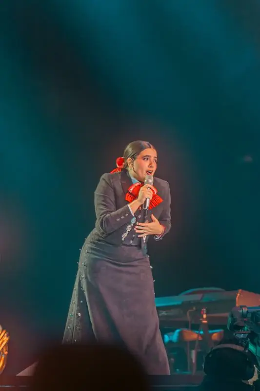 Woman in a dark outfit with red accents singing