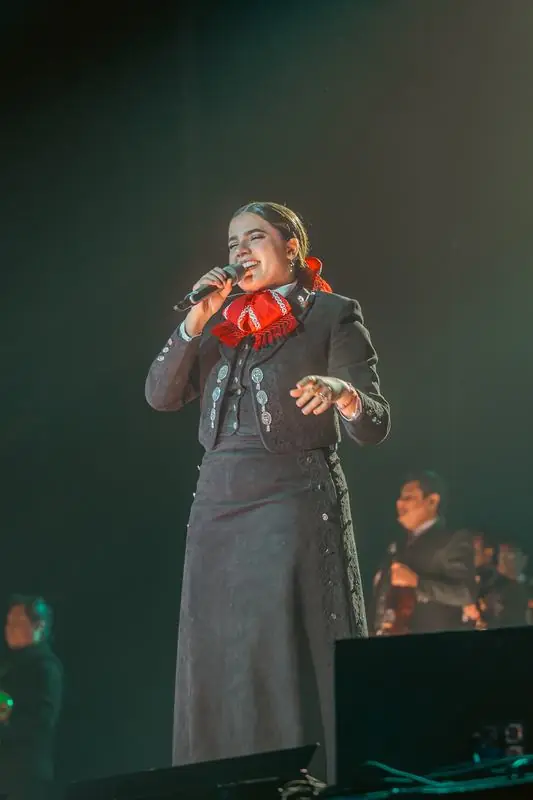 Woman in traditional Mexican attire singing on stage