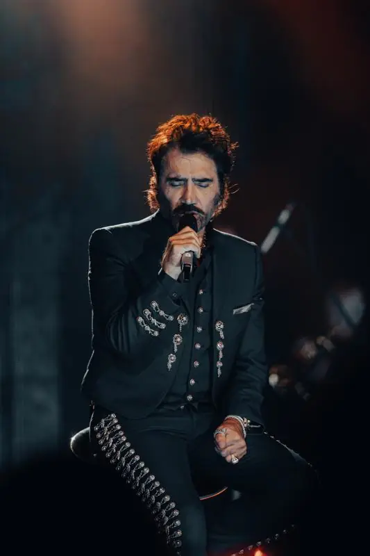 Man in a black embellished outfit singing