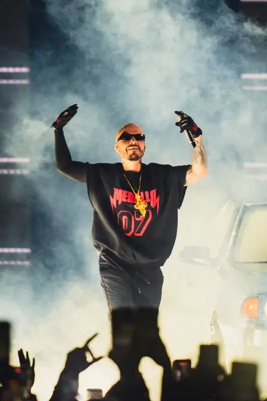 Artist waving on stage with a car and fog