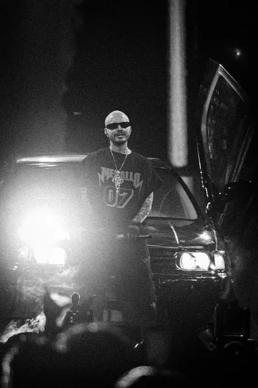 Black and white photo of a man in front of a car